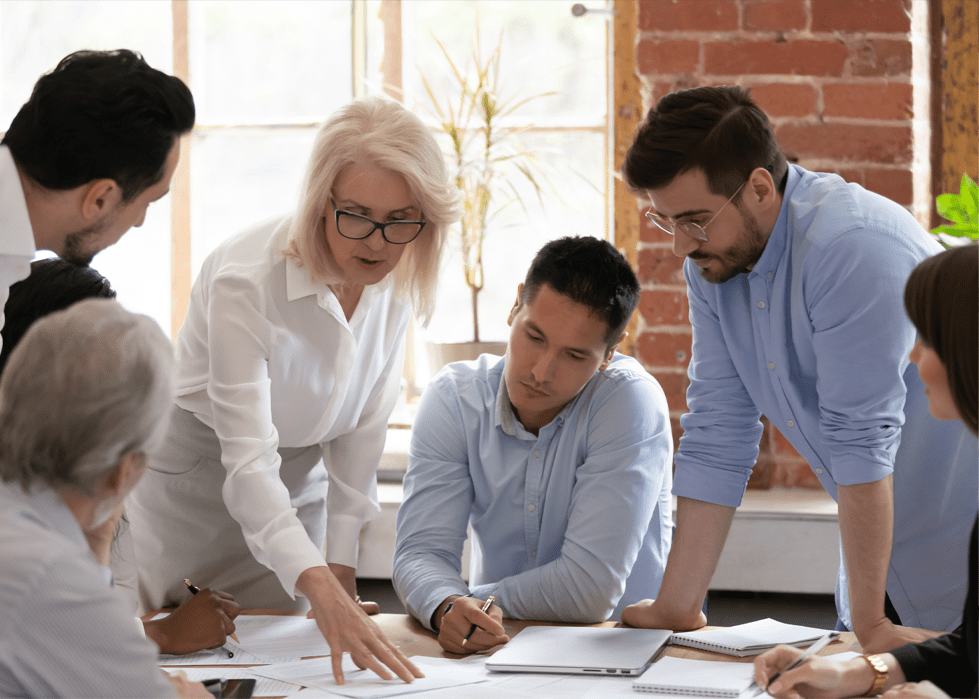 men and women around a table working on a project and learn- Zeevou Academy