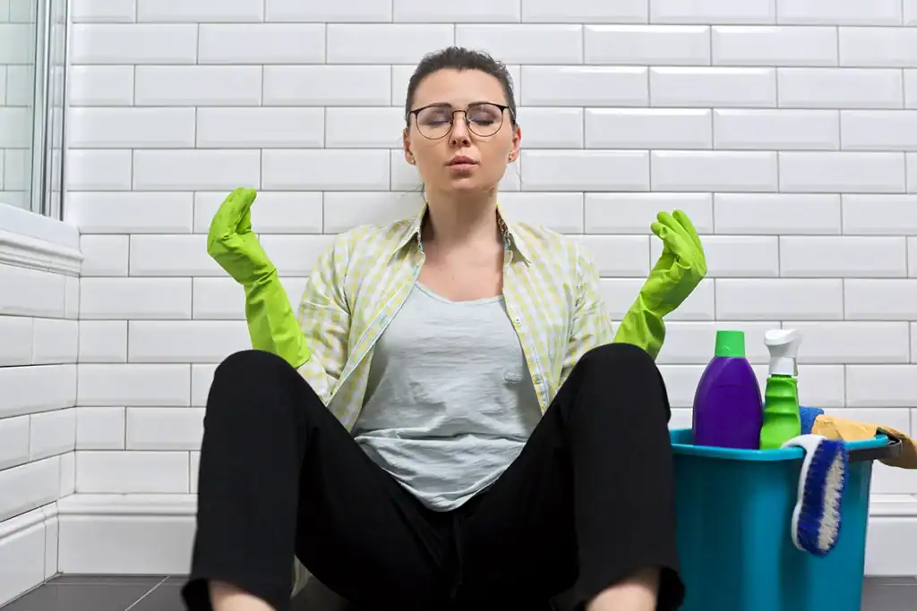Housekeeper taking a break in a guest bathroom, representing the coordination challenge behind multi-property cleaning schedules - Zeevou